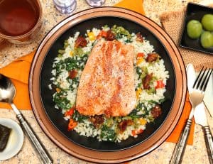 Salmon with Riced Cauliflower and Vegetable Salad at table with hot Tea and castelvetrano olives. This meal is both Whole30 diet and Paleo approved.