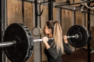 Young woman working out with a barbell, using the squat exercise.