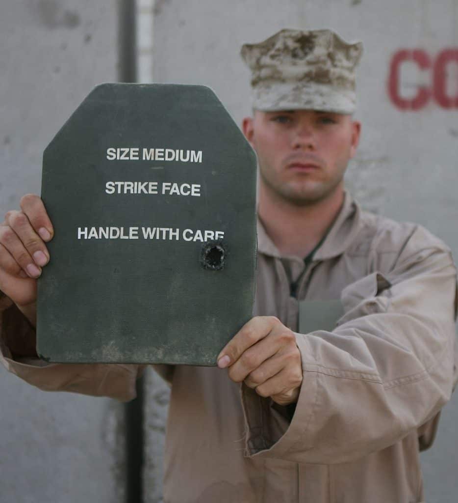 Cpl. Brandon L. Blair holds out the enhanced small-arms protective insert plate that stopped a gunshot against him.